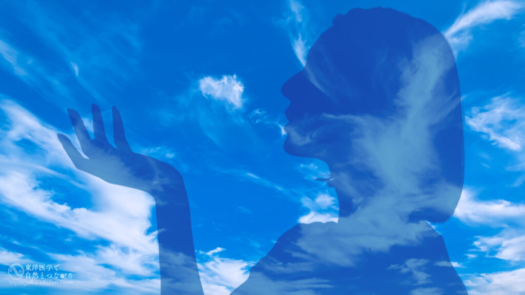 二十四節気「処暑（しょしょ）」のイメージ。すじ雲（巻雲）が浮かぶ秋の空を背景に、空気が乾燥しはじめているのを感じている女性のシルエット